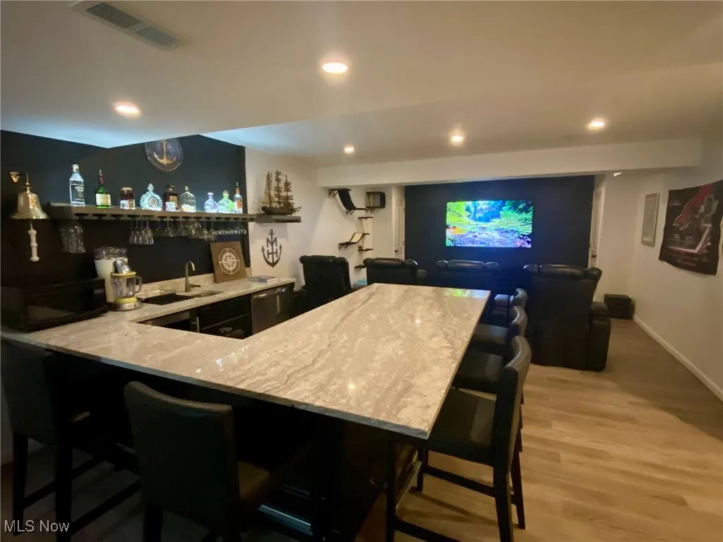 The lower-level bar is a standout feature, with a sleek granite countertop and a stylish brass footrail that adds a touch of elegance. A well-lit liquor shelf is conveniently within reach, making it the perfect setup for your personal bartender to craft the ideal cocktail. It’s an entertainer’s dream, designed for both function and flair.