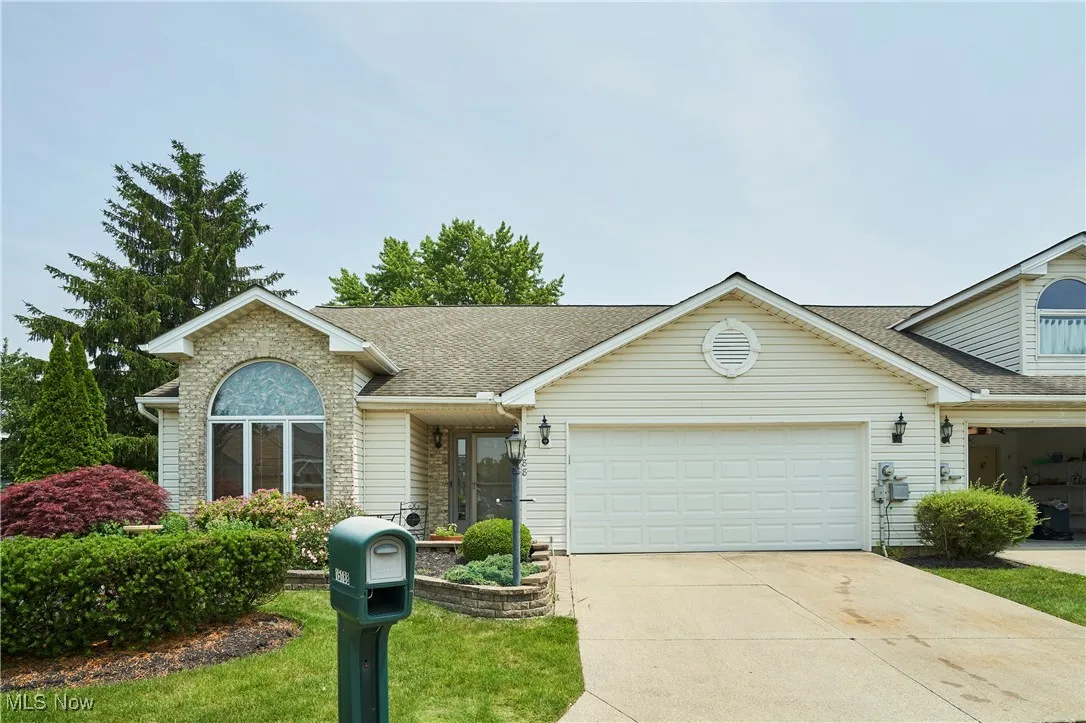 View of front of house featuring a garage, concrete driveway, and roof with shingles