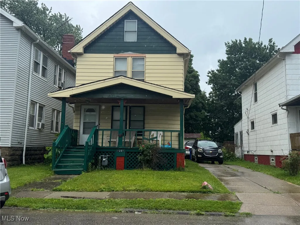 American foursquare style home featuring covered porch, concrete driveway, and a front lawn