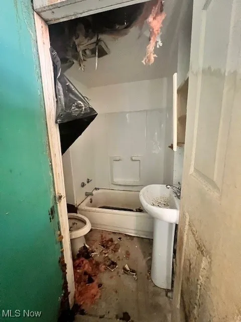 Bathroom featuring unfinished concrete flooring and tub / shower combination
