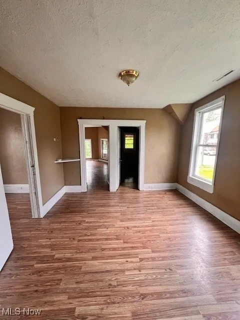 Spare room with wood finished floors and a textured ceiling