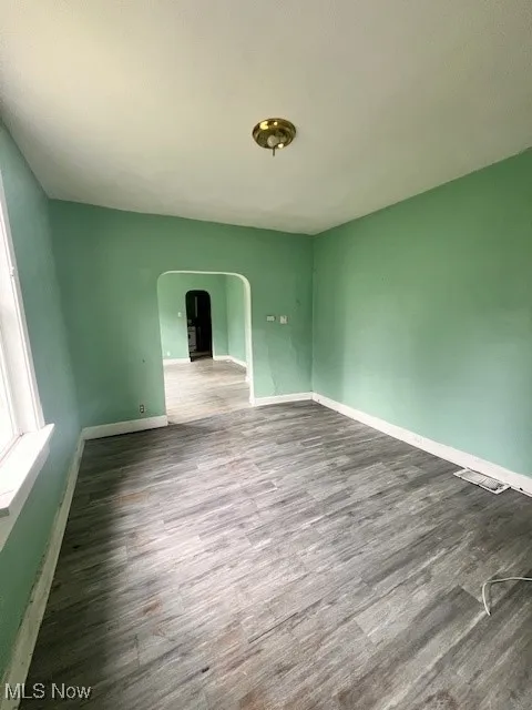 Spare room with arched walkways and wood finished floors