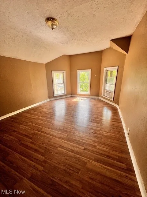 Unfurnished room featuring wood finished floors, a textured ceiling, and a textured wall