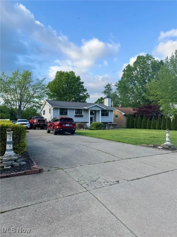 View of front of home featuring concrete driveway, a front lawn, and a chimney