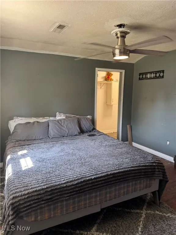 Bedroom featuring wood finished floors, a textured ceiling, and a ceiling fan