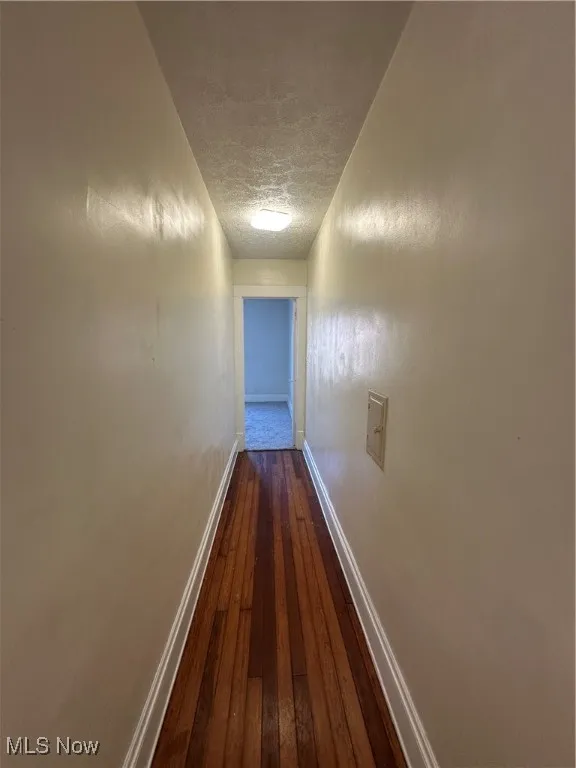 Corridor with dark wood-type flooring and a textured ceiling