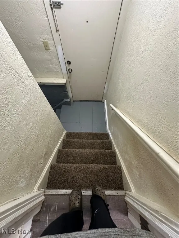 Staircase with a textured wall and tile patterned floors