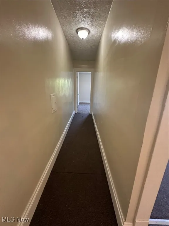 Hall with a textured ceiling and carpet floors