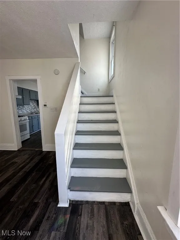 Stairway featuring wood finished floors and a textured ceiling