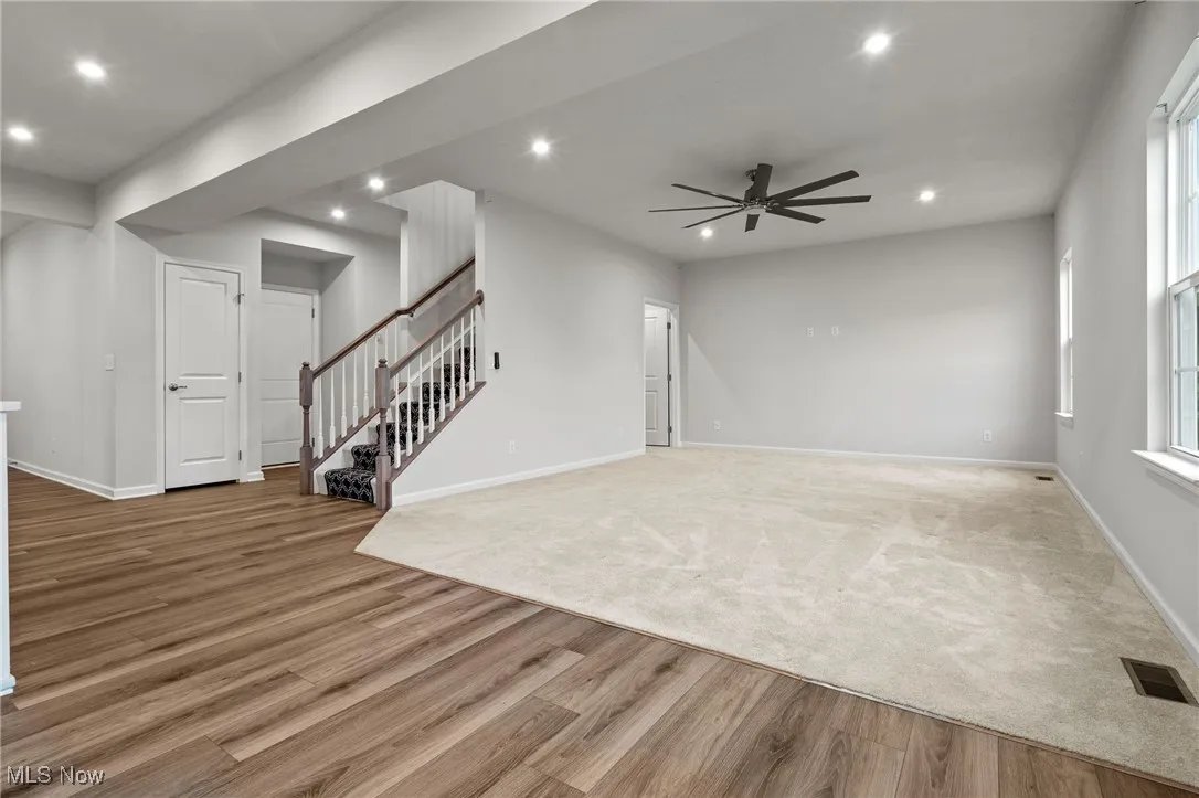 Unfurnished living room featuring recessed lighting, light wood finished floors, a ceiling fan, and stairway