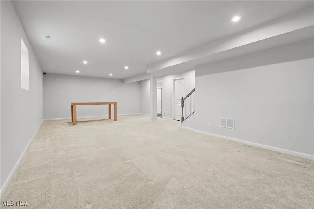 Finished basement featuring light carpet, stairway, and recessed lighting