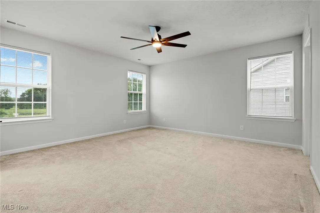 Carpeted empty room featuring ceiling fan and baseboards