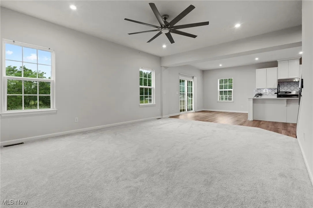 Unfurnished living room with light colored carpet, recessed lighting, and a ceiling fan