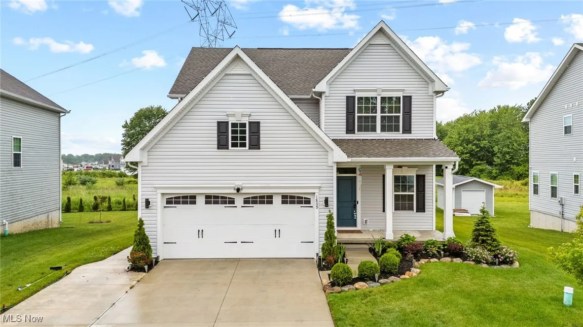 Traditional home featuring a porch, a front lawn, concrete driveway, roof with shingles, and a garage