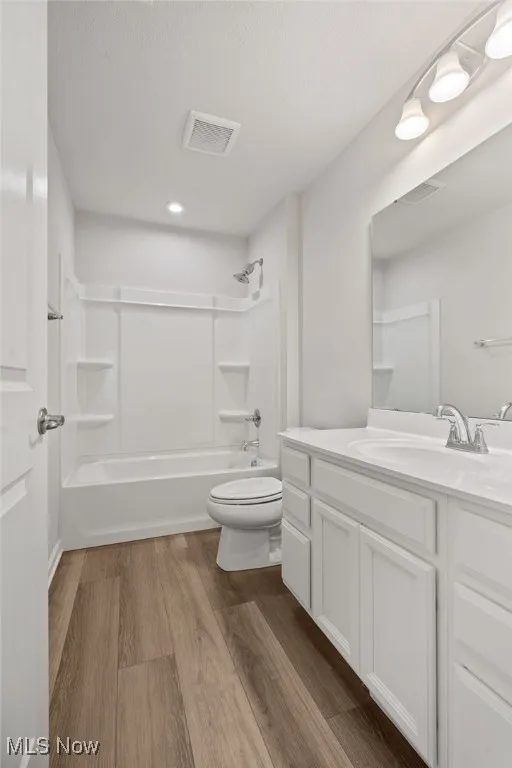 Bathroom with vanity, wood finished floors, washtub / shower combination, a textured ceiling, and recessed lighting