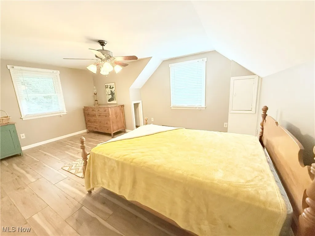 Bedroom with light wood-style floors, a ceiling fan, and vaulted ceiling