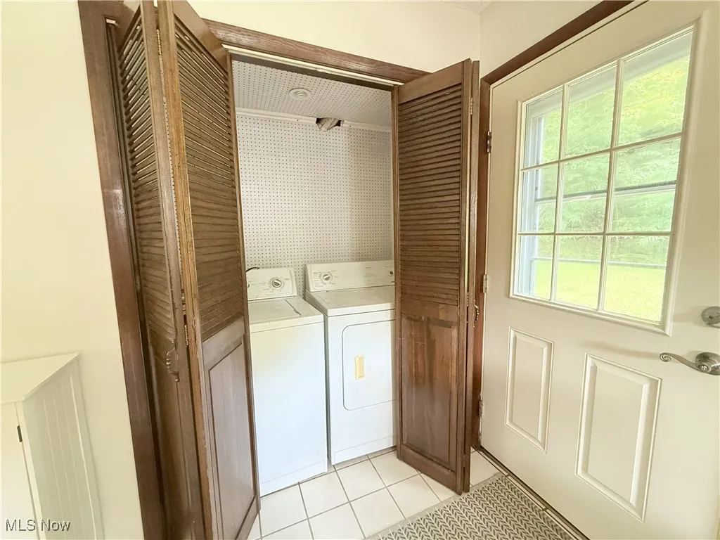 Laundry area with separate washer and dryer and light tile patterned flooring