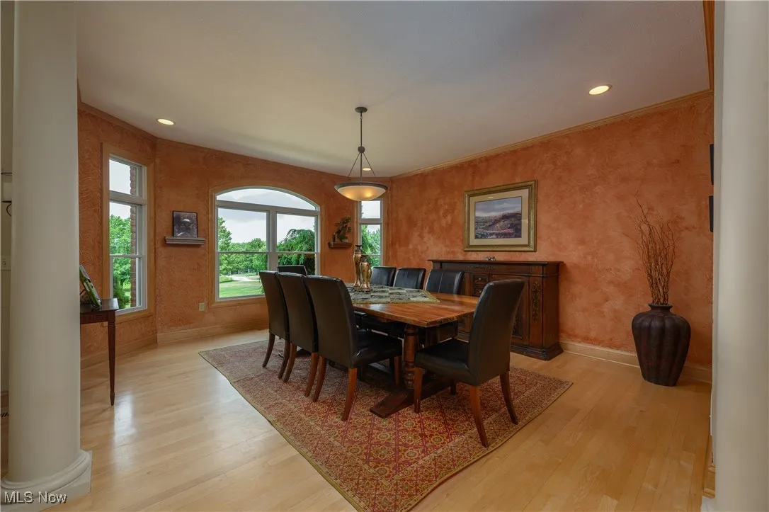 Dining area featuring light wood-style flooring, ornate columns, and recessed lighting