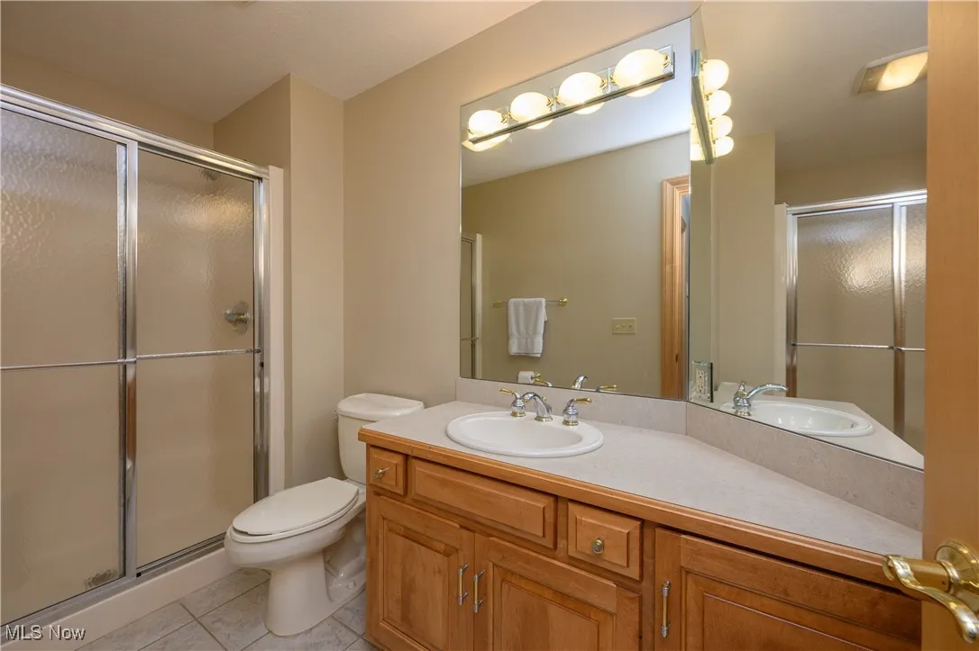 Full bathroom featuring a shower stall, vanity, and tile patterned flooring