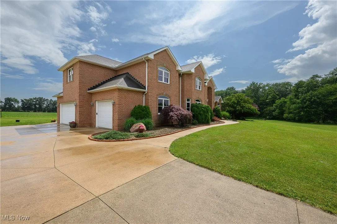 View of home's exterior featuring concrete driveway, brick siding, a lawn, and a garage