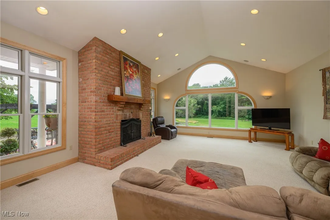 Living room with carpet floors, plenty of natural light, a fireplace, vaulted ceiling, and recessed lighting