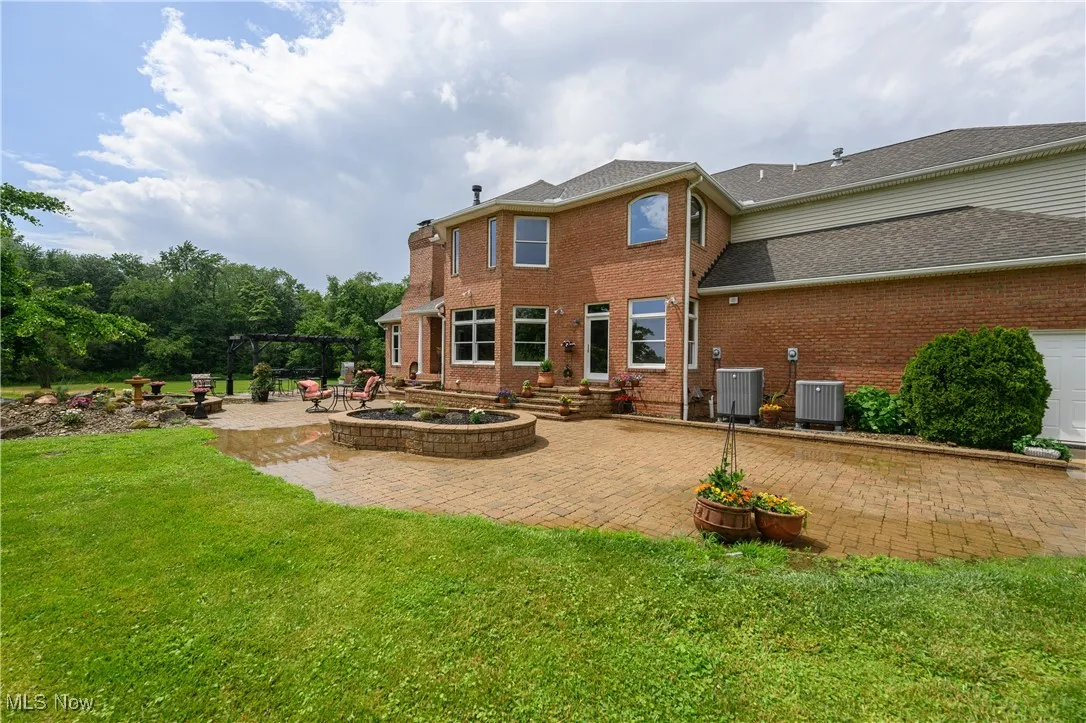 Rear view of property featuring a pergola, a patio area, brick siding, and a yard