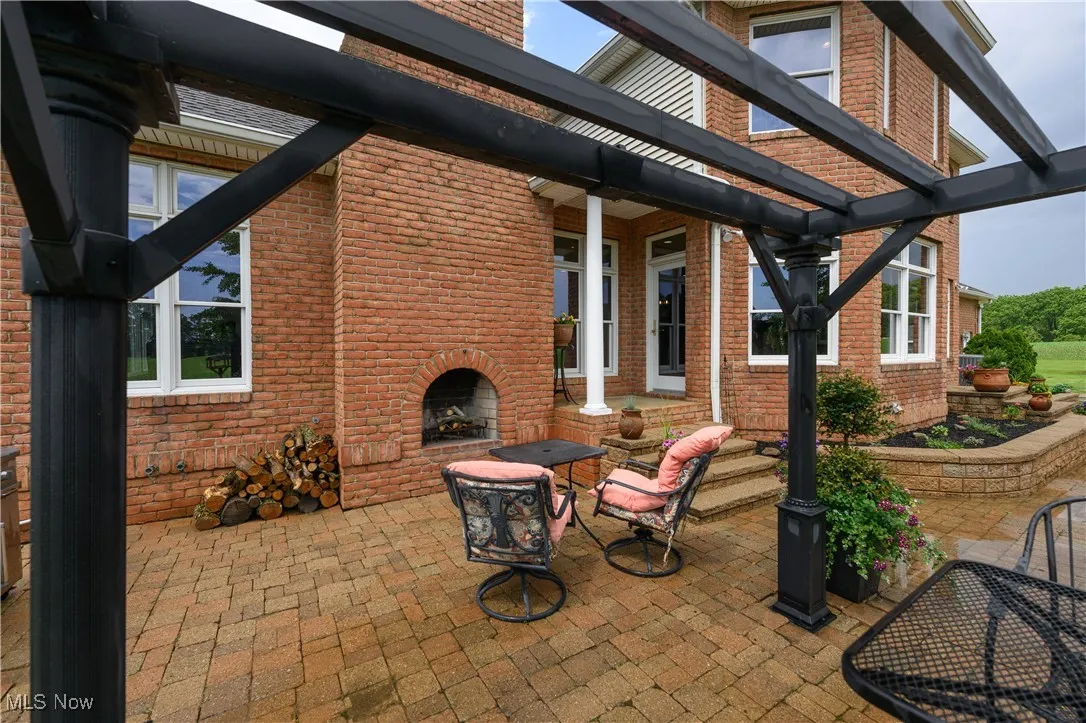 View of patio with an outdoor brick fireplace