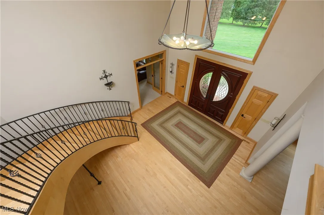 Foyer entrance with a high ceiling, a chandelier, wood finished floors, arched walkways, and plenty of natural light