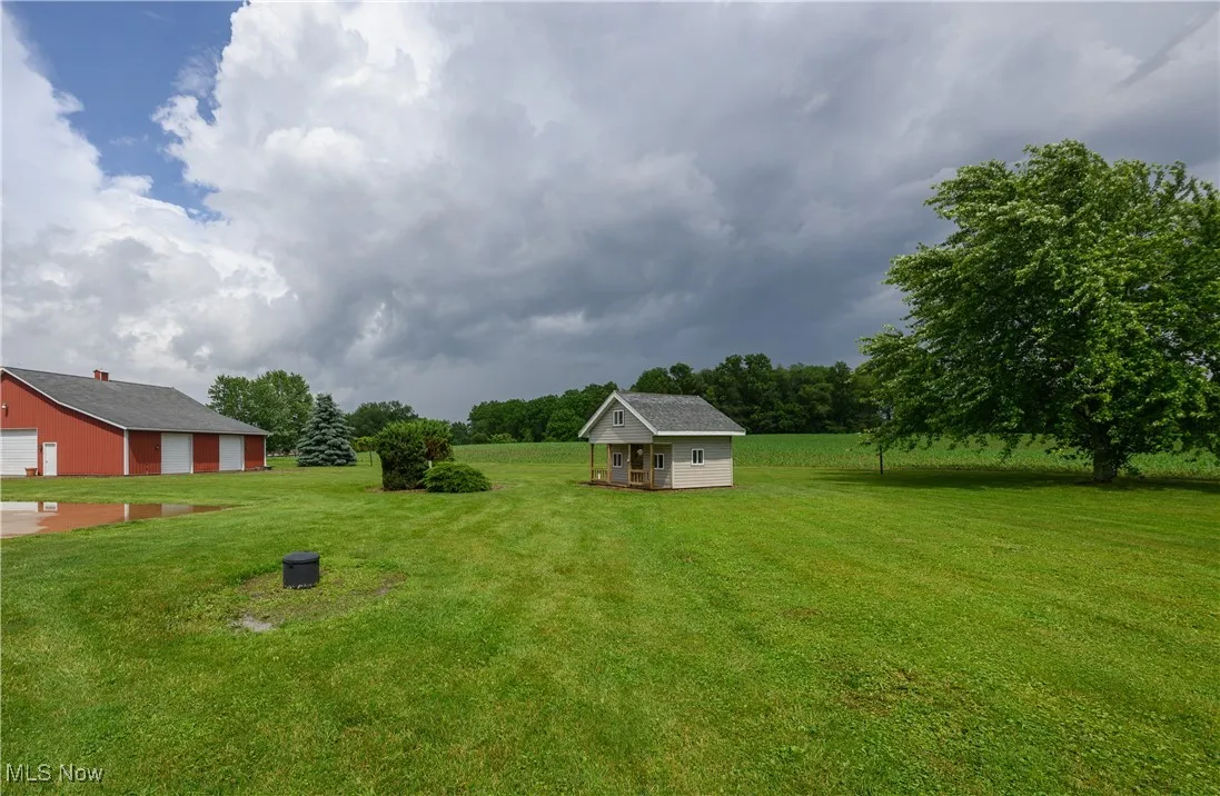View of green lawn featuring an outdoor structure and a detached garage