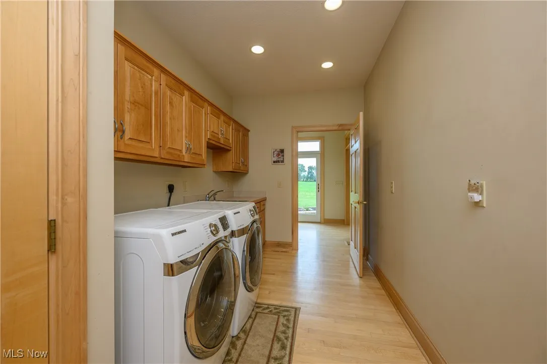 Washroom featuring independent washer and dryer, light wood-type flooring, recessed lighting, and cabinet space
