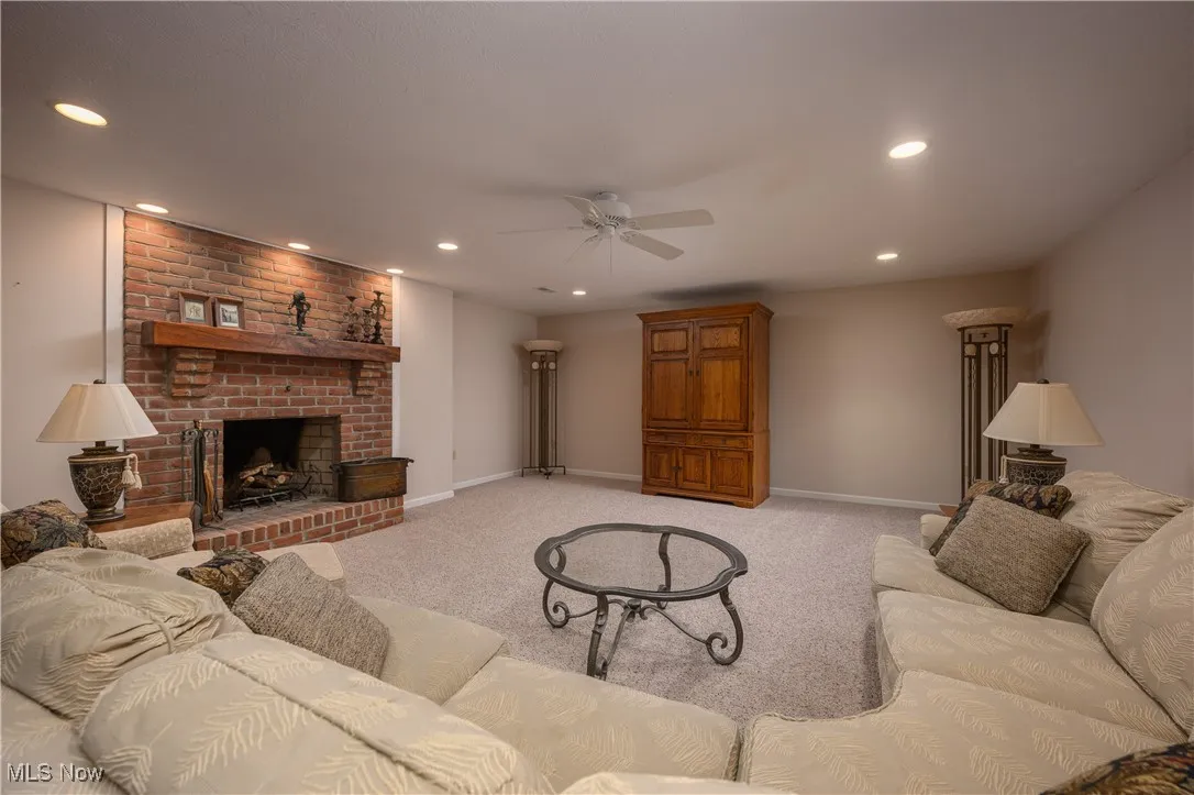 Living room with ceiling fan, light carpet, recessed lighting, and a fireplace