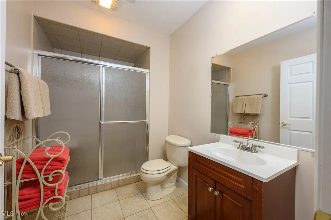 Full bath with vanity, tile patterned floors, and a shower stall
