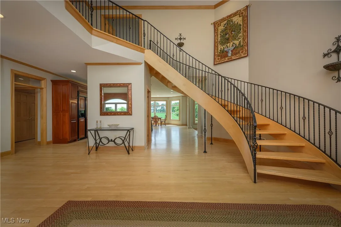 Stairs featuring wood finished floors, crown molding, a high ceiling, and recessed lighting