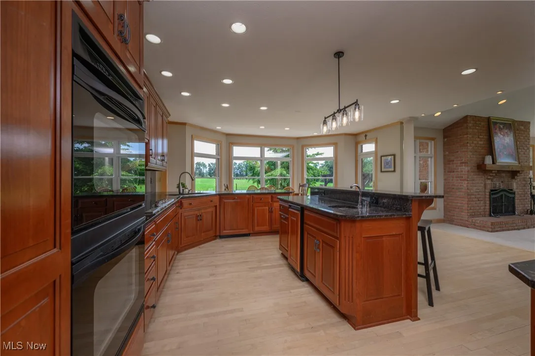 Kitchen featuring a kitchen breakfast bar, open floor plan, light wood-type flooring, brown cabinets, and recessed lighting