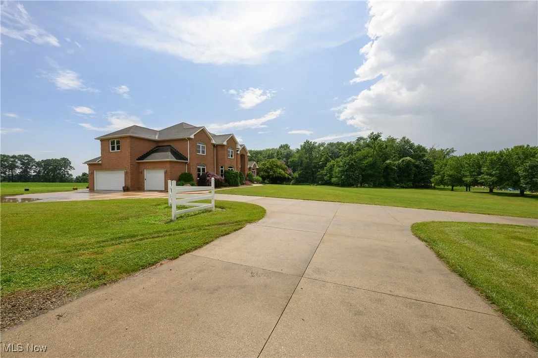 Traditional-style home featuring curved driveway, a front lawn, an attached garage, and brick siding
