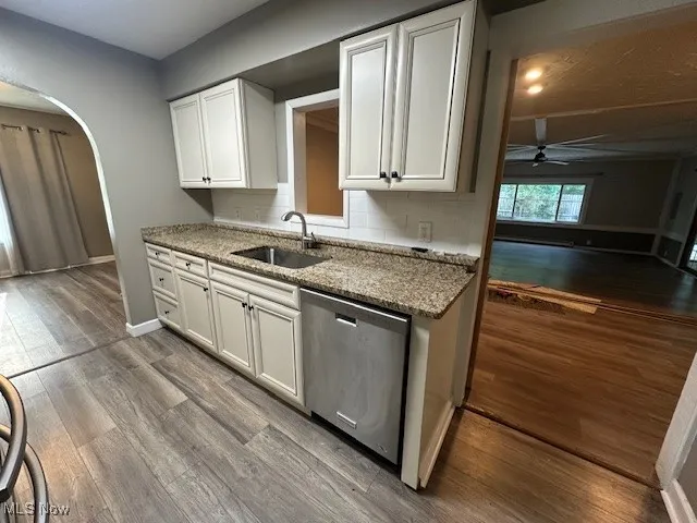 Kitchen with dishwasher, ceiling fan, white cabinetry, light stone countertops, and wood finished floors