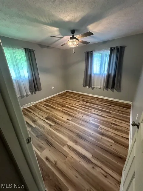Unfurnished room with ceiling fan, a textured ceiling, and wood finished floors