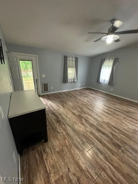 Unfurnished living room with a ceiling fan and dark wood-style flooring