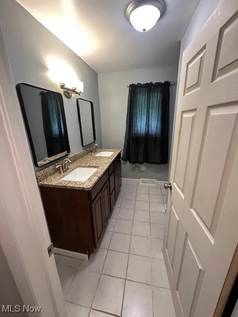Full bath with double vanity and tile patterned flooring