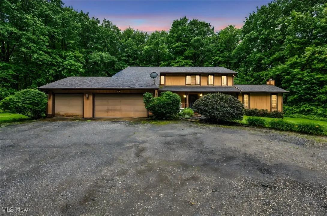 View of front of house with a garage, a chimney, and driveway