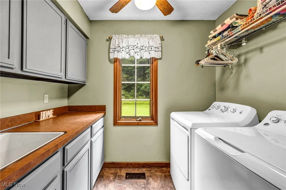 Laundry room with washing machine and dryer, cabinet space, and a ceiling fan