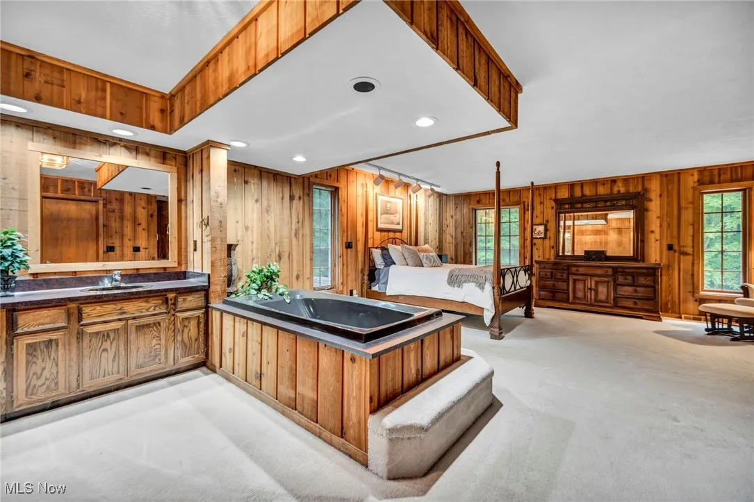 Bedroom featuring wooden walls, light carpet, and recessed lighting