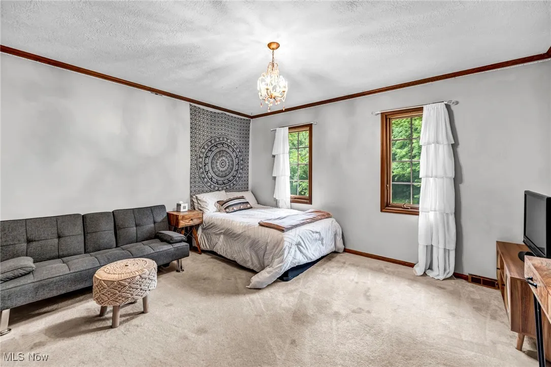 Bedroom featuring crown molding, a chandelier, light colored carpet, and a textured ceiling