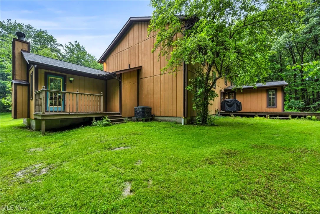 Rear view of property with a chimney, a yard, and a deck