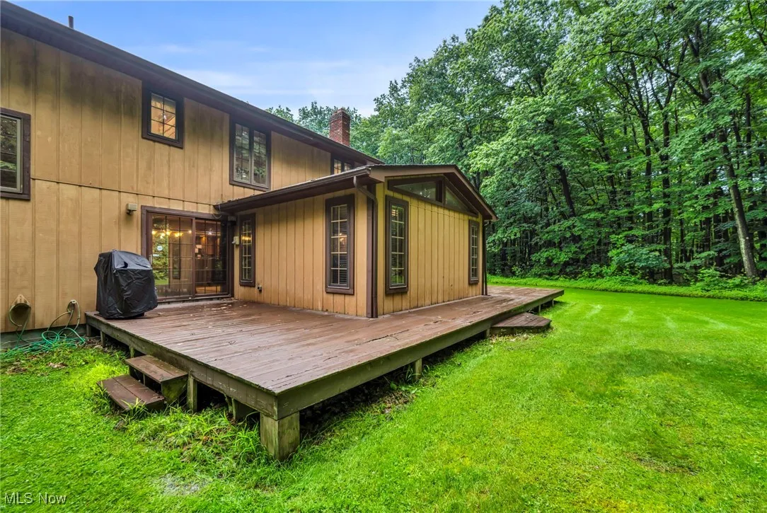 Wooden terrace featuring area for grilling and a lawn