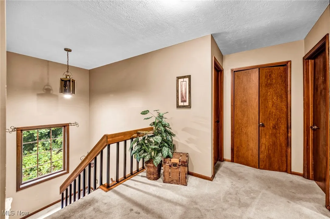 Corridor with an upstairs landing, carpet flooring, and a textured ceiling