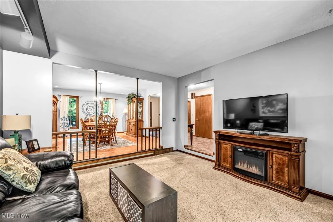 Living area with carpet floors, a glass covered fireplace, and a chandelier