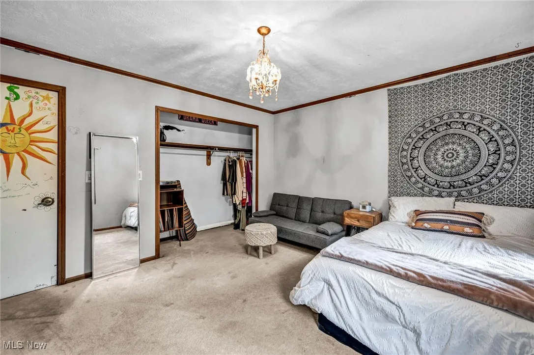 Carpeted bedroom with a chandelier, a closet, and crown molding