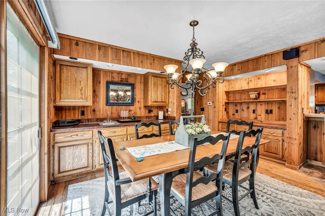 Dining area featuring wood walls, a chandelier, and light wood finished floors