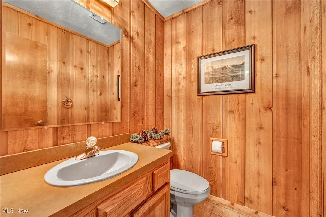 Bathroom with vanity, wood walls, and tile patterned floors